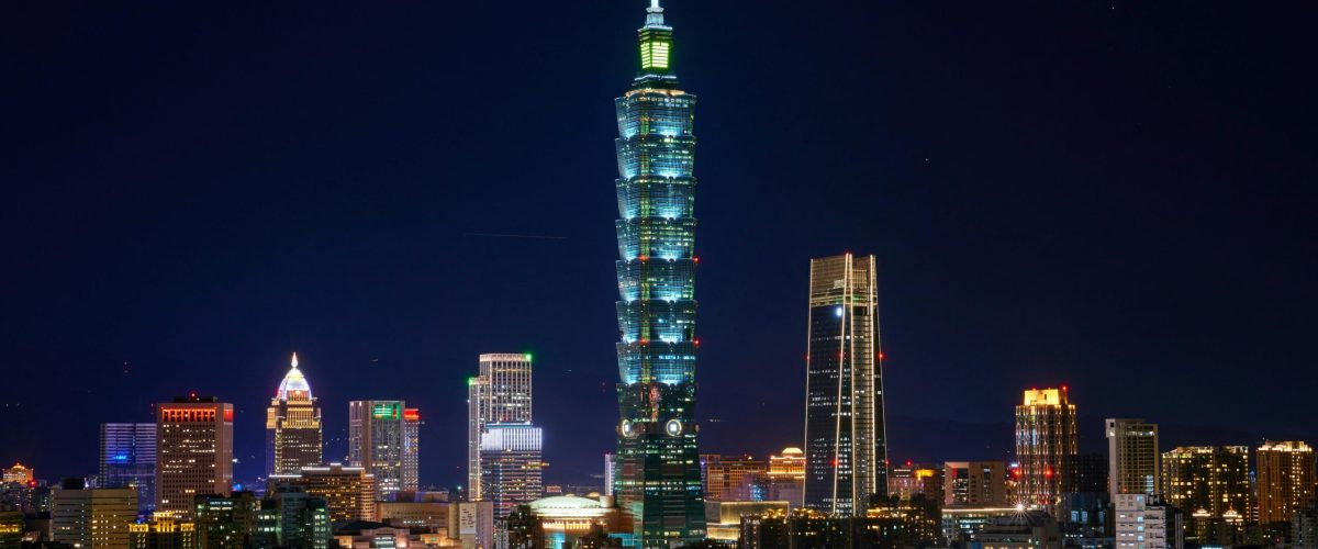 Illuminated Taipei 101 and city skyline at night showcasing modern urban architecture.